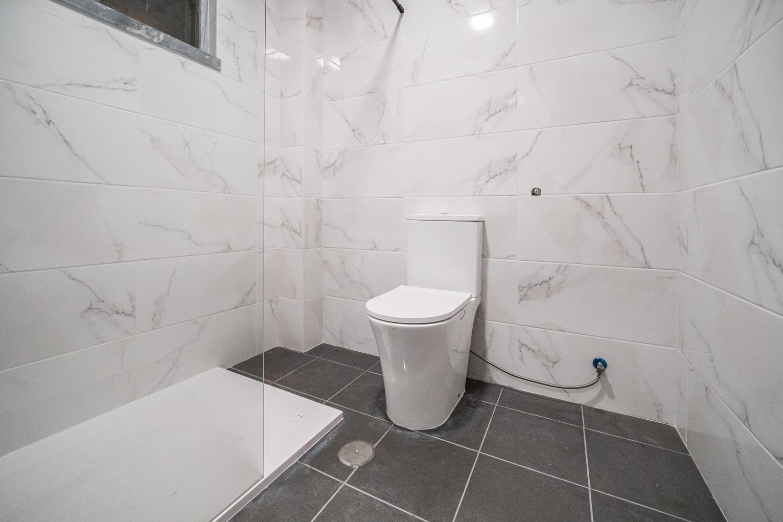 Elegant modern bathroom featuring a walk-in shower, sink, and toilet with a stylish wooden finish.